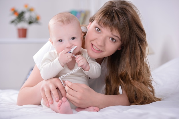 Bonne maman et bébé jouant sur le lit à la maison.