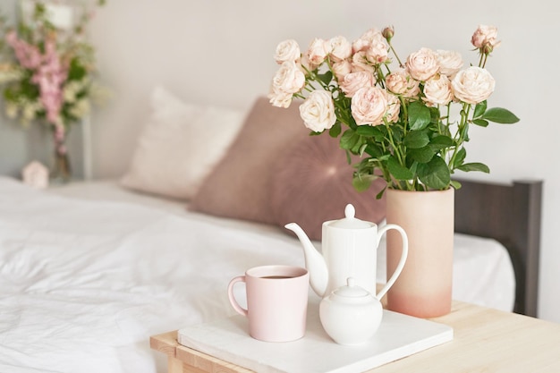 Bonne matinée confortable Bouquet de fleurs roses dans un vase sur la table Chambre d'hôtel avec lit Arrivée à l'hôtel Repos et détente Café au lit Petit déjeuner romantique Saint Valentin