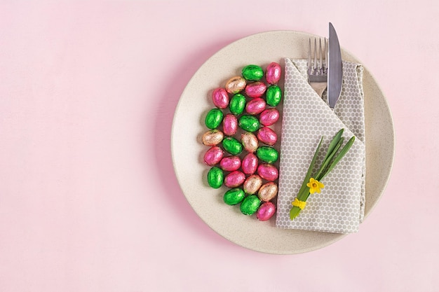 Bonne Pâques Table mise en place pour les vacances de Pâques œufs de Pâque fleur et couverts sur fond rose Vue supérieure à plat