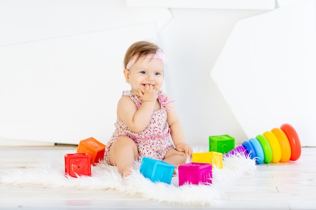 Bonne petite fille assise dans une salle blanche dans une robe rouge avec des jouets lumineux