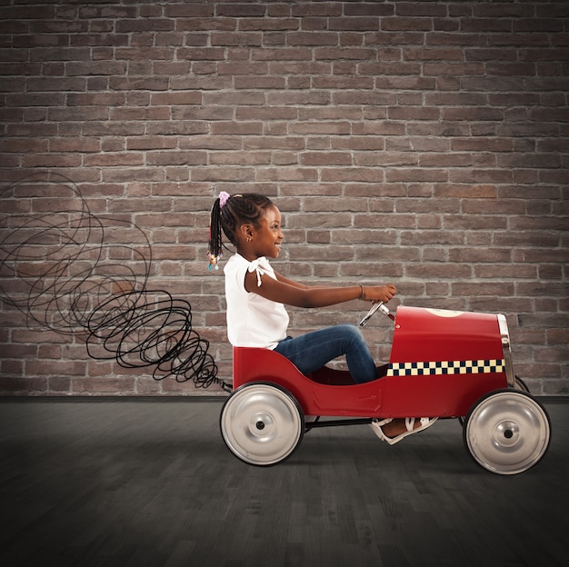 Bonne petite fille au volant d'une petite voiture