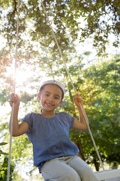 Bonne petite fille sur une balançoire dans le parc