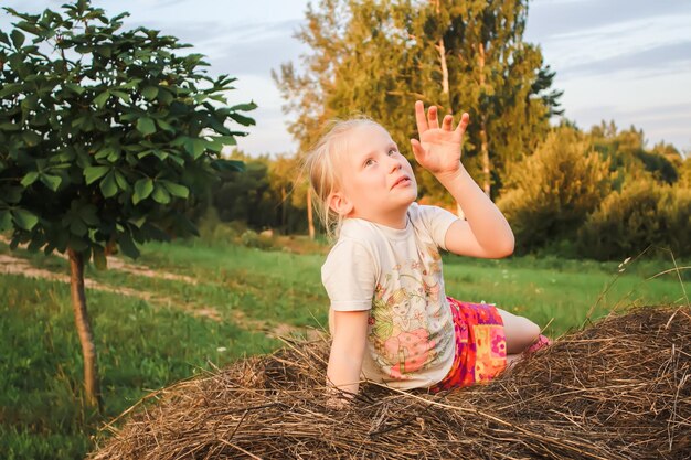 Bonne petite fille sur une botte de foin à la campagne