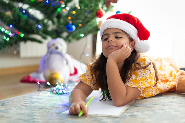 Bonne petite fille caucasienne pensant à la liste de souhaits de Noël