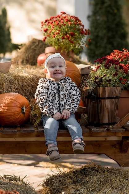 Bonne petite fille avec des citrouilles dans le parc en automne rit