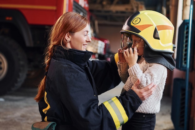 Bonne petite fille est avec une pompière en uniforme de protection