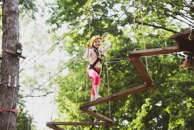Bonne petite fille grimpant sur une aire de jeux de corde en plein air enfance insouciante