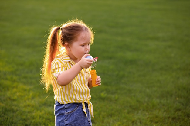 Bonne petite fille jouant avec des bulles de savon dans le parc