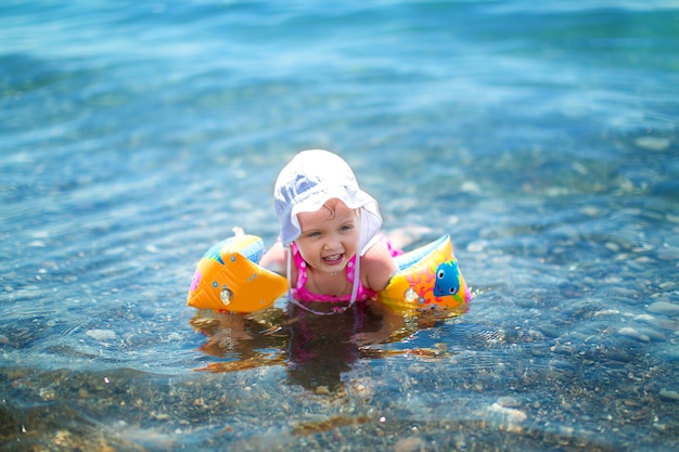 Bonne petite fille jouant dans la mer en vacances d'été