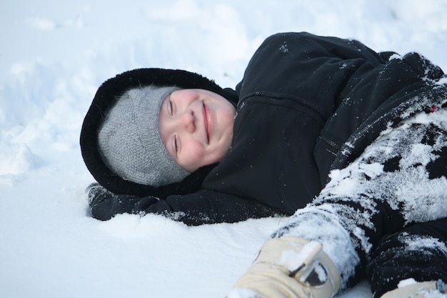 Bonne petite fille jouant avec des extérieurs de neige en hiver dans la campagne