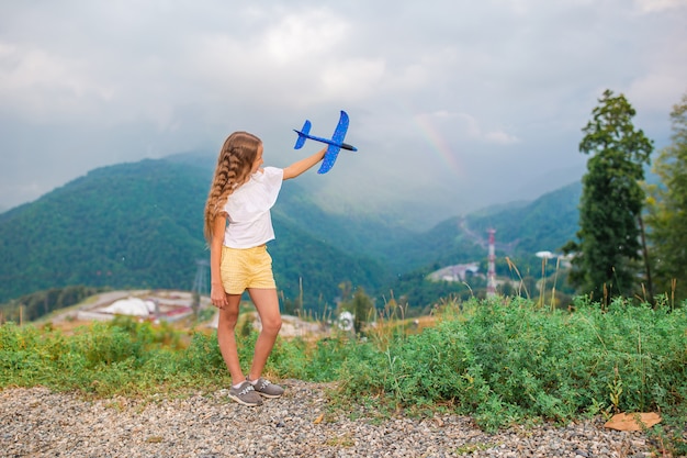 Bonne petite fille avec jouet avion en mains dans les montagnes