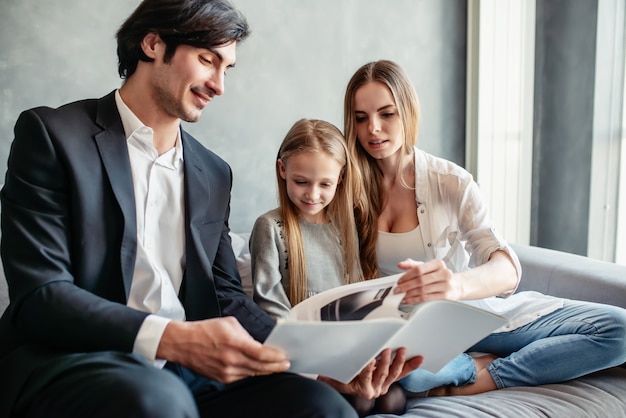 Bonne petite fille lit un livre avec ses parents à la maison