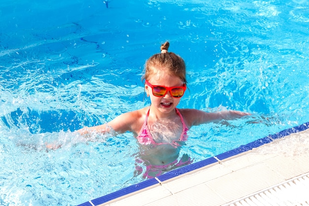 Bonne petite fille nageant dans la piscine en vacances en été