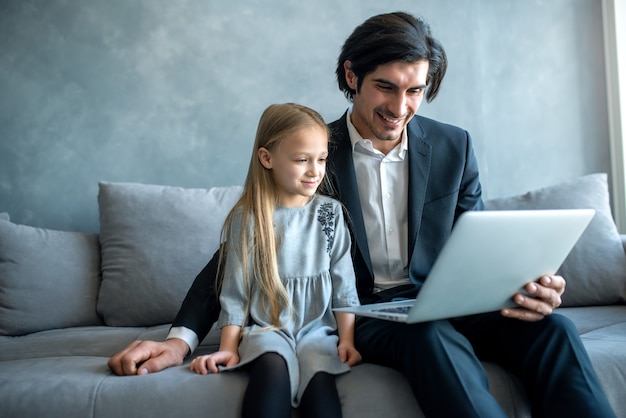 Bonne petite fille regardant un film sur l'ordinateur avec son père à la maison