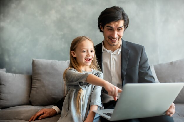 Bonne petite fille regardant un film sur l'ordinateur avec son père à la maison