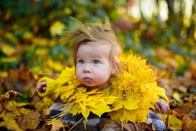 Bonne petite fille rit et joue à l'extérieur. Sur le cou, il y a un collier de feuilles d'automne.