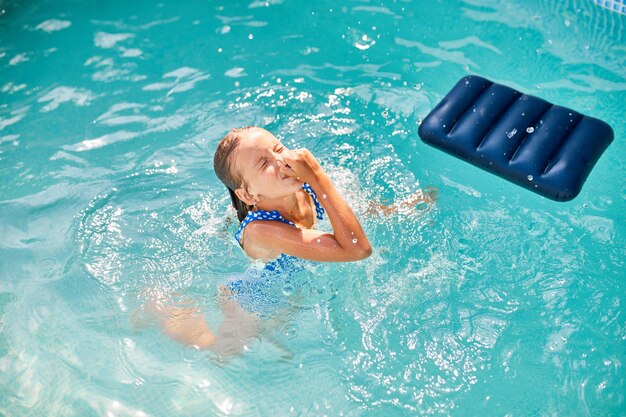 Bonne petite fille s'amusant dans la piscine plonge et nage