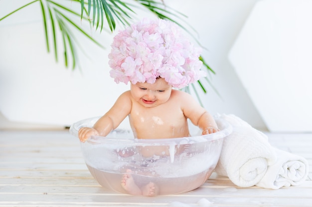 Bonne petite fille se lave dans un bassin avec de la mousse et de l'eau