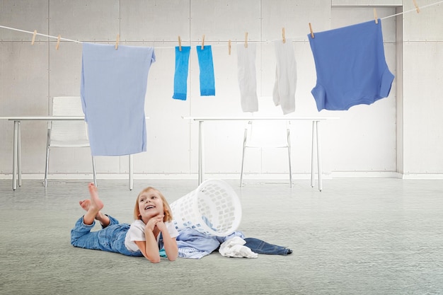 Bonne petite fille avec un seau de vêtements lavés. Technique mixte