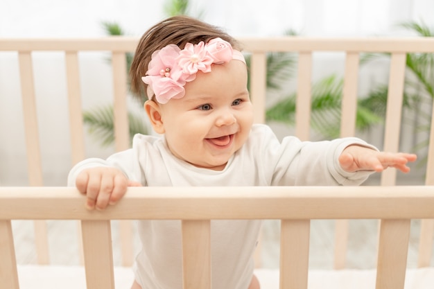 Bonne petite fille de six mois debout dans la crèche