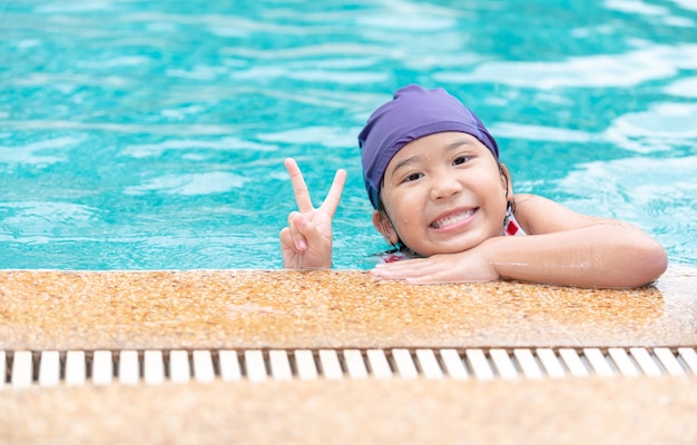 Bonne petite fille sourit et porte un bonnet de bain