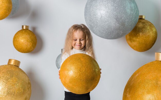 Bonne petite fille tenant une énorme boule de Noël