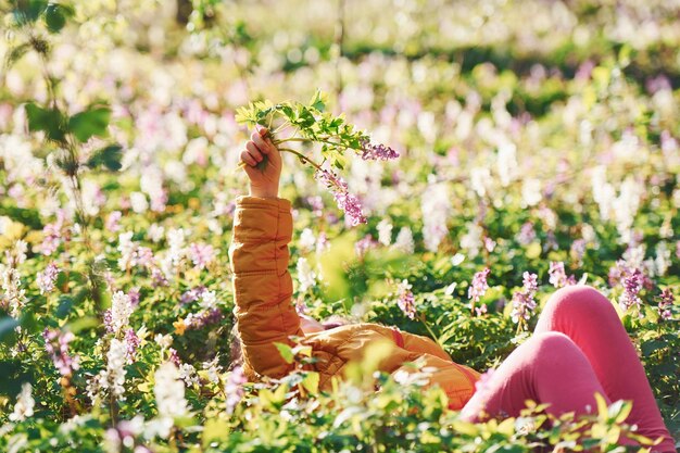 Bonne petite fille en tenue décontractée allongée sur le sol dans la forêt de printemps pendant la journée