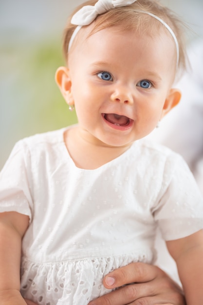 Photo bonne petite fille vêtue de blanc riant portant un bandeau et des boucles d'oreilles.