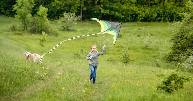 Bonne petite fille volant cerf-volant lumineux à l'extérieur sur la nature au printemps