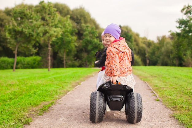 Bonne petites filles mignonnes conduire une moto à l'extérieur