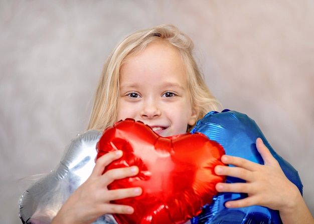 Bonne Saint Valentin coeur. Petite fille appuie sur sa poitrine coeur gonflable rose sur fond violet clair.