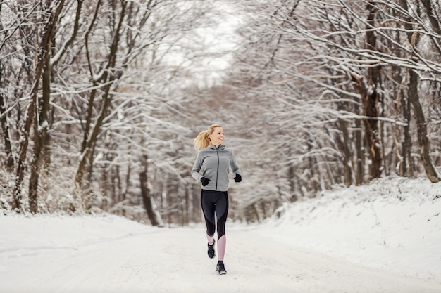 Bonne sportive fit jogging dans la nature au jour d'hiver enneigé. Vie saine, sports d'hiver
