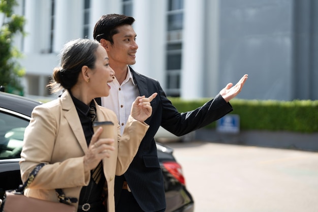 Bonne vieille femme d'affaires asiatique âgée discutant d'un nouveau projet avec un jeune collègue masculin asiatique au parking