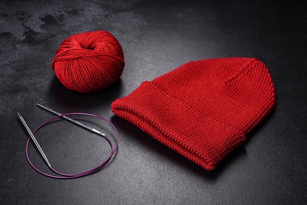 Bonnet de femme tricoté rouge chaud sur fond de béton Passe-temps et loisirs