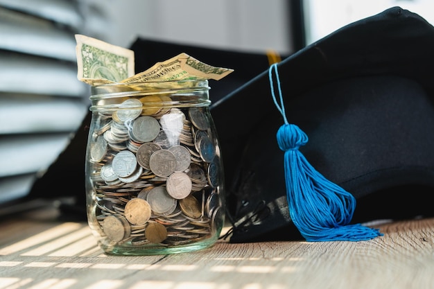 Le bonnet de graduation noir et le pot de pièces en argent investissent dans l'éducation L'obtention du diplôme économise de l'argent pour l'éducation