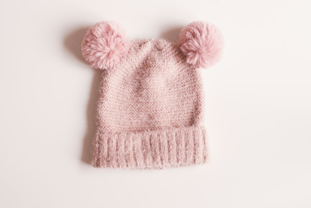 Bonnet en laine tricoté de couleur rose avec pompons sur fond blanc. Vêtements chauds d'automne ou d'hiver