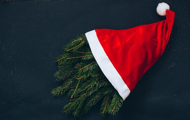 Bonnet de Noël rouge avec sapin sur fond noir. Vue de dessus.