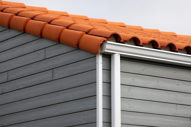 Bord d'égouttement de fascia de système de protection de gouttière blanche sur un quartier de maison familiale en bois gris unique