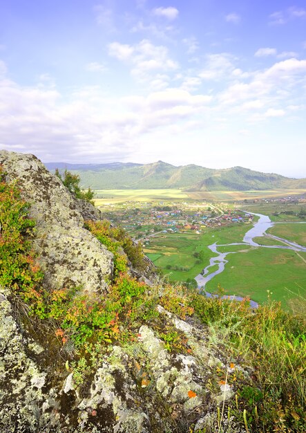 Le bord d'une falaise au-dessus d'une vallée de montagne sous un ciel bleu nuageux. Sibérie, Russie