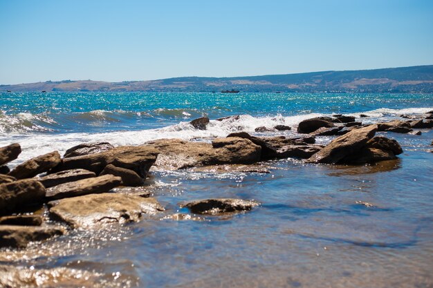 Bord de mer rocheux. Paysage d'été. L'eau scintille et bat contre les pierres.