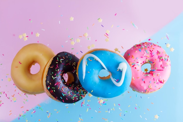 Bordure de beignets tombant - mélange de beignets sucrés multicolores avec des pépites sur fond bleu et rose