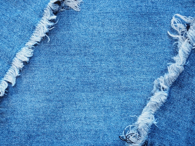 Bordure en denim bleu déchirée sur la texture d&#39;un jean