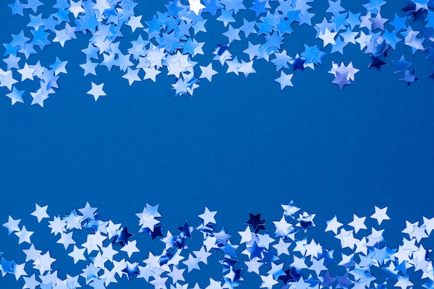 Bordure de fond de Noël abstrait bleu, texture de trame avec des confettis étoiles sur fond bleu. Espace pour le texte.