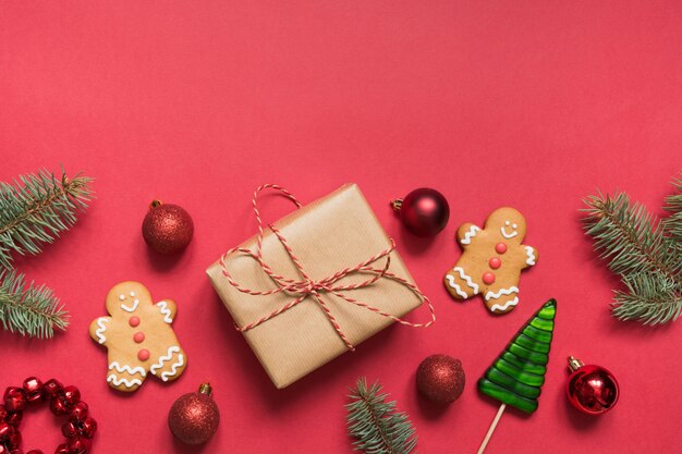 Bordure de Noël de boîte-cadeau, branches à feuilles persistantes, biscuits au pain d'épice sur le rouge. Vacances de Noël.