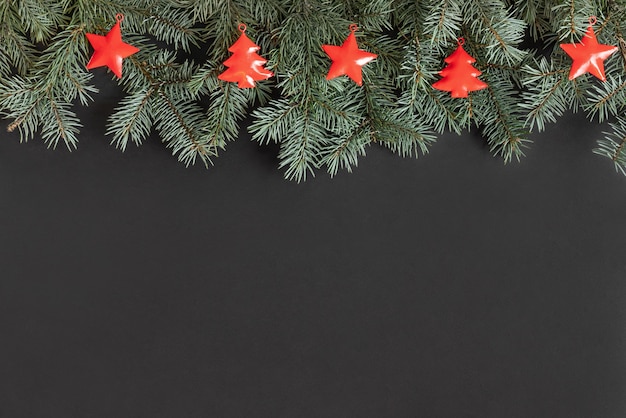 Bordure de Noël avec des branches de sapin et des décorations de Noël rouges sur fond noir.