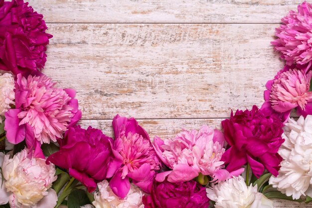 Bordure de pivoines sur un fond en bois avec un espace vide pour le texte