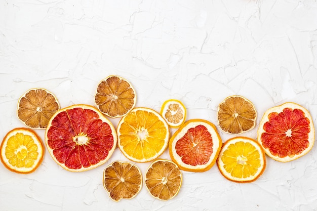 Bordure de tranches séchées de divers agrumes sur fond blanc. Surface de pamplemousse orange citron