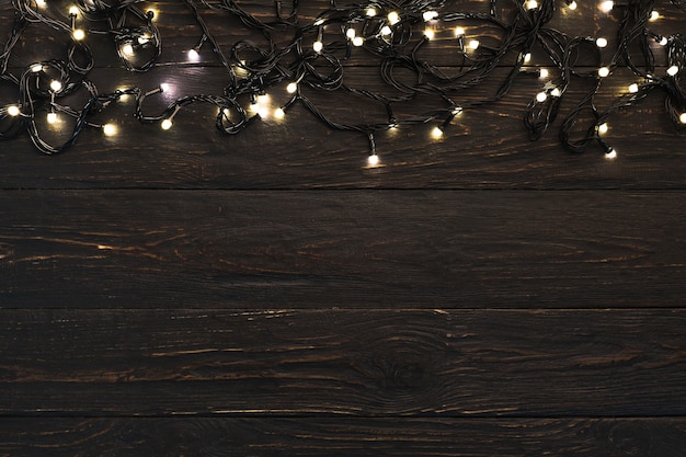Bordure de vacances de guirlande lumineuse sur des planches de bois marron, vue de dessus