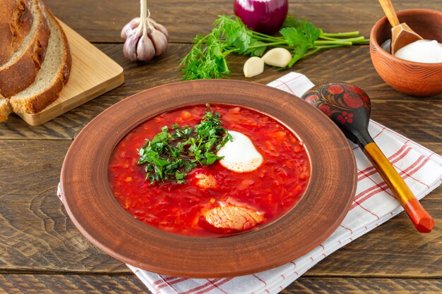 Borsch - soupe de betteraves traditionnelle ukrainienne et russe sur fond de bois foncé. Servi avec pain de seigle, ail et sel.