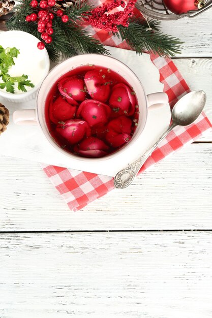 Bortsch rouge clair polonais traditionnel avec boulettes et décorations de Noël sur table en bois